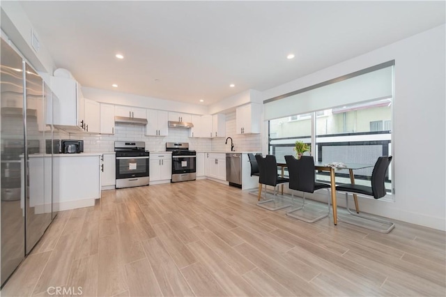5652 La Mirada Ave, Los Angeles, CA 90038 - kitchen featuring a sink, tasteful backsplash, appliances with stainless steel finishes, light countertops, and light wood-style floors