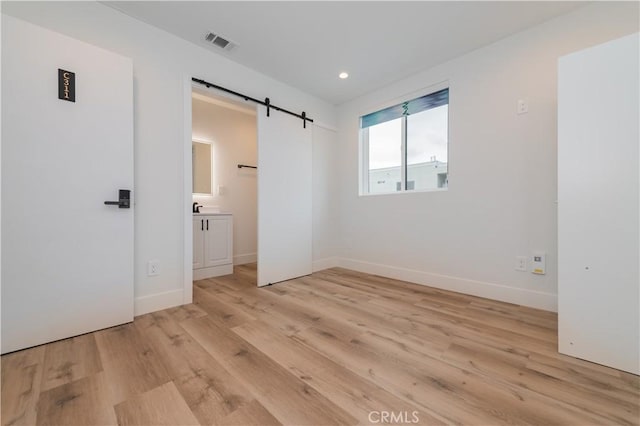 5652 La Mirada Ave, Los Angeles, CA 90038 - unfurnished bedroom with light wood-type flooring, visible vents, a barn door, and baseboards