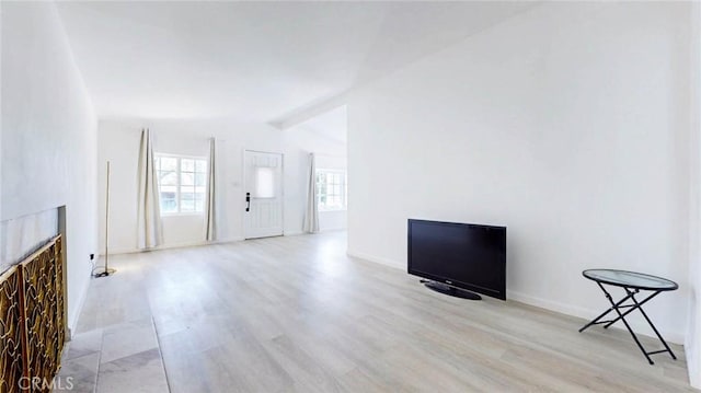 unfurnished living room with lofted ceiling, wood finished floors, a fireplace, and baseboards