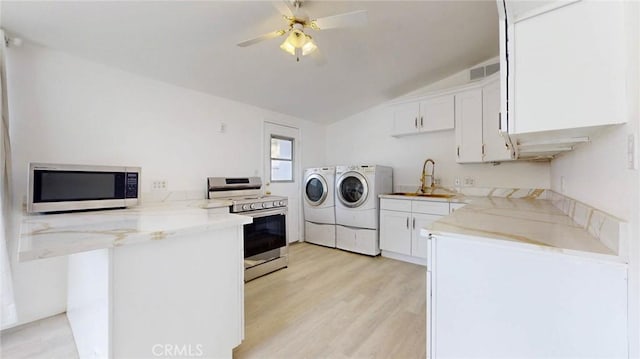clothes washing area with a sink, light wood-style floors, ceiling fan, visible vents, and washer and clothes dryer