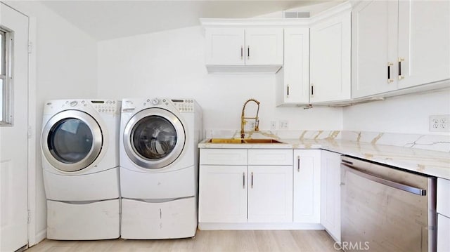 laundry room with light wood-type flooring, washer and clothes dryer, laundry area, and a sink