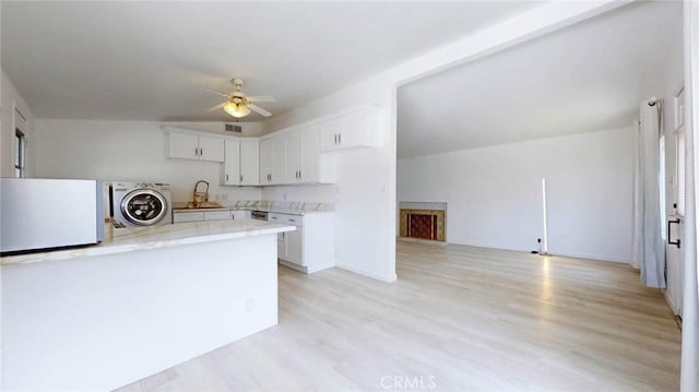 kitchen with white refrigerator, white cabinets, light wood finished floors, washer / clothes dryer, and a ceiling fan