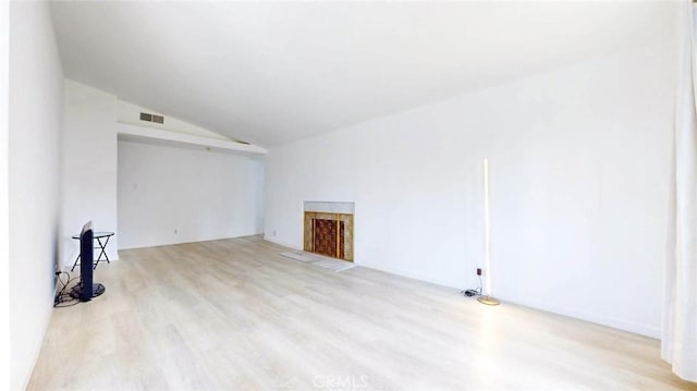 unfurnished living room with a fireplace, wood finished floors, visible vents, and lofted ceiling