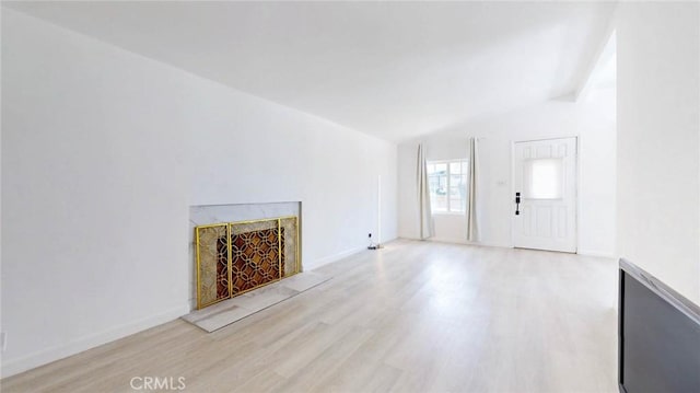 unfurnished living room featuring wood finished floors, a high end fireplace, and baseboards