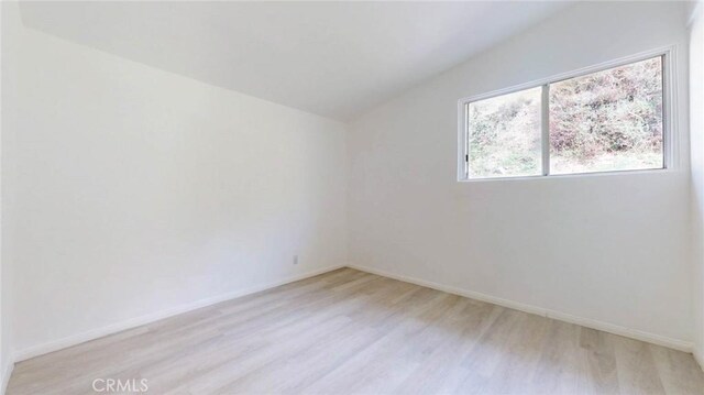 spare room with baseboards and light wood-style flooring