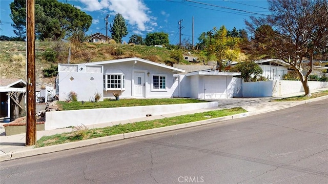 view of front facade with a garage, fence, stucco siding, and concrete driveway