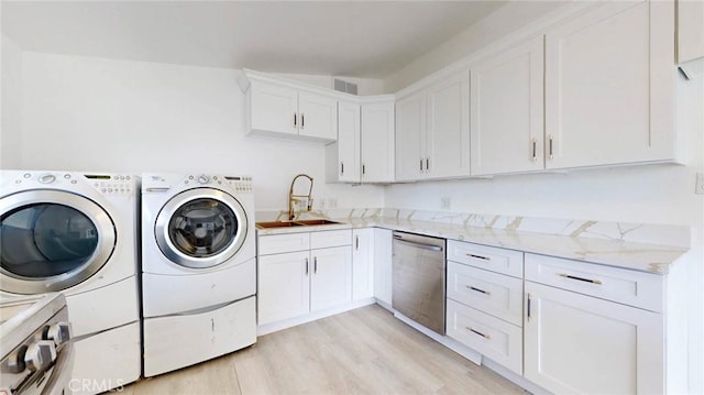 laundry room with visible vents, washer and dryer, light wood-style flooring, and a sink