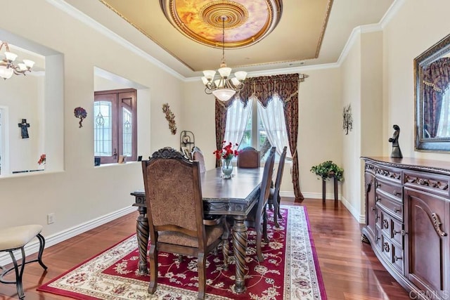 dining area featuring crown molding, dark wood-style flooring, a tray ceiling, and an inviting chandelier