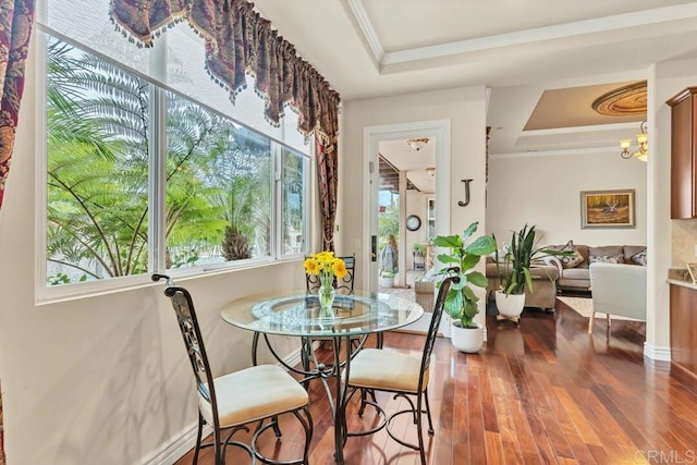 dining room featuring a chandelier, ornamental molding, wood finished floors, and a raised ceiling