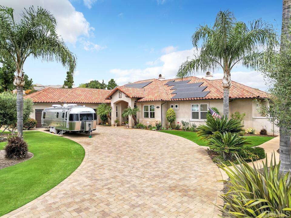 2070 Zlatibor Ranch Rd, Escondido, CA 92025 - mediterranean / spanish house featuring curved driveway, stucco siding, a front yard, and solar panels