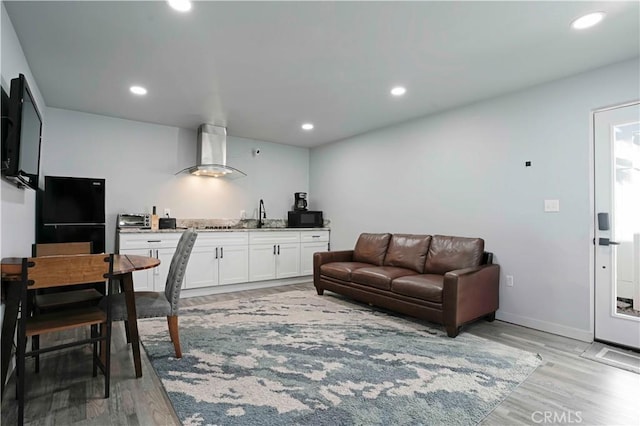 living room with recessed lighting, wet bar, baseboards, and light wood-style floors