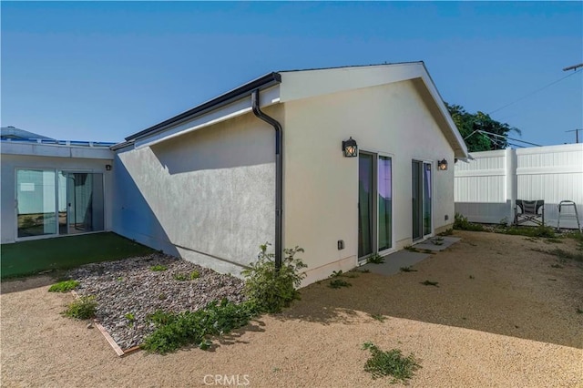 view of home's exterior featuring stucco siding and fence
