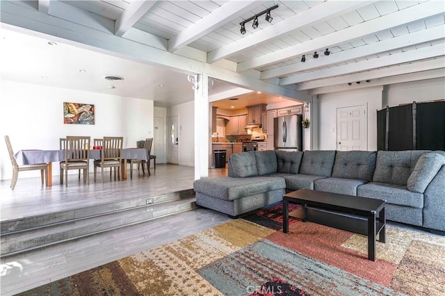 living area with beamed ceiling and light wood-style floors