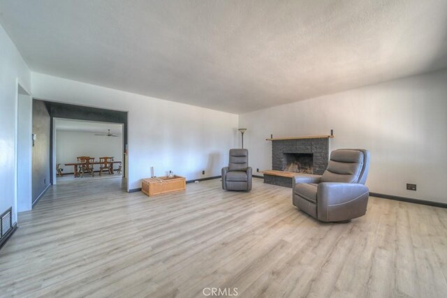 living area featuring baseboards, wood finished floors, and a fireplace