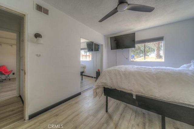 bedroom with visible vents, a ceiling fan, light wood-style floors, and multiple windows