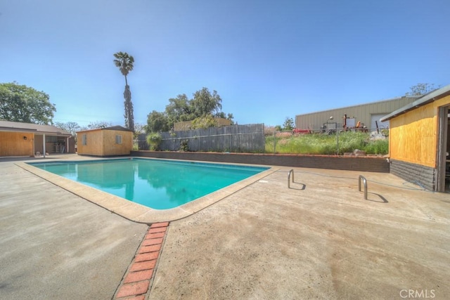 view of swimming pool featuring fence, an outdoor structure, a patio, and a fenced in pool