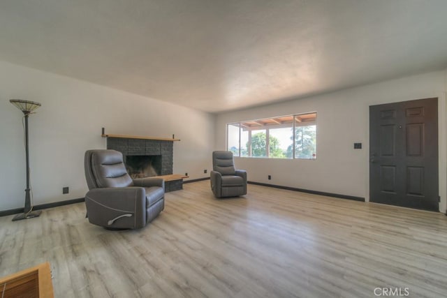 living room with baseboards, visible vents, wood finished floors, and a fireplace with raised hearth