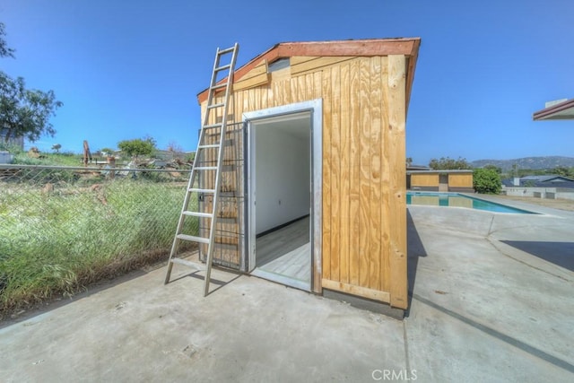 view of outdoor structure with an outbuilding, an outdoor pool, and fence