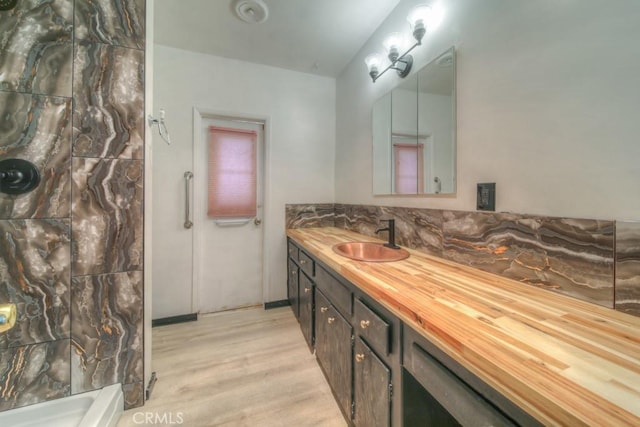 bathroom featuring vanity, a shower, wood finished floors, and tasteful backsplash