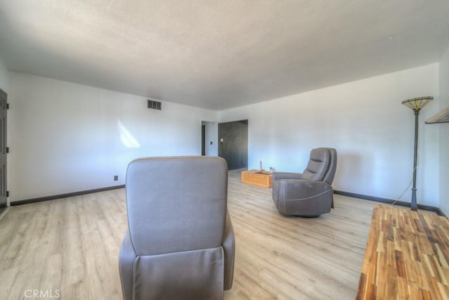 sitting room with baseboards, visible vents, and wood finished floors