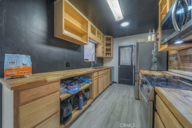kitchen with wooden counters, open shelves, appliances with stainless steel finishes, and a sink