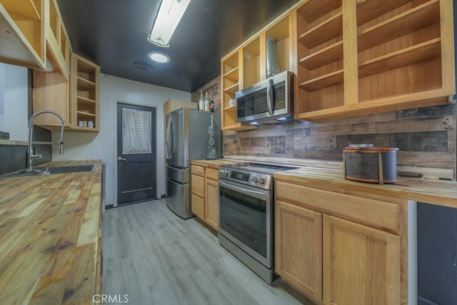 kitchen with stainless steel appliances, butcher block countertops, open shelves, and a sink