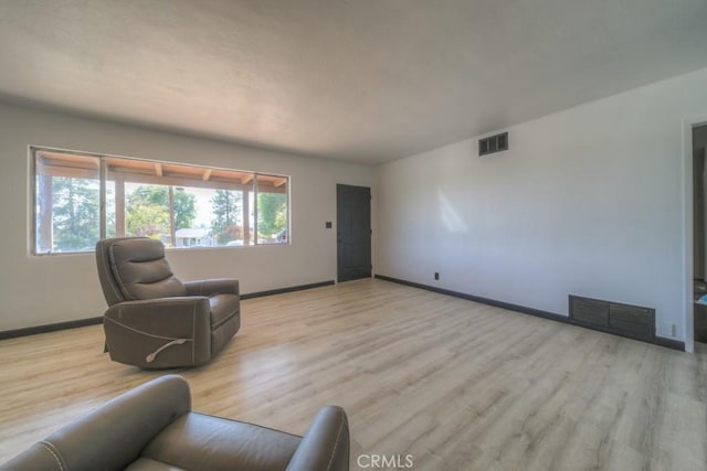 living area featuring light wood finished floors, visible vents, and baseboards