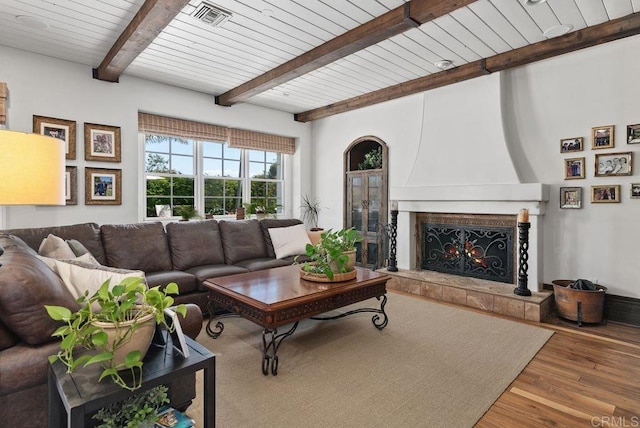 living room with visible vents, wood finished floors, beamed ceiling, wooden ceiling, and a premium fireplace