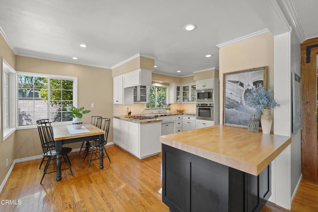 kitchen featuring light wood finished floors, a sink, glass insert cabinets, white cabinetry, and appliances with stainless steel finishes
