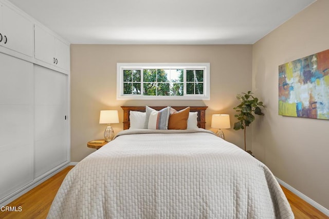 bedroom featuring baseboards, a closet, and light wood-style flooring