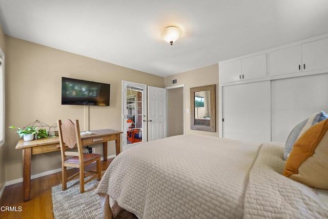 bedroom featuring baseboards, visible vents, wood finished floors, and a closet