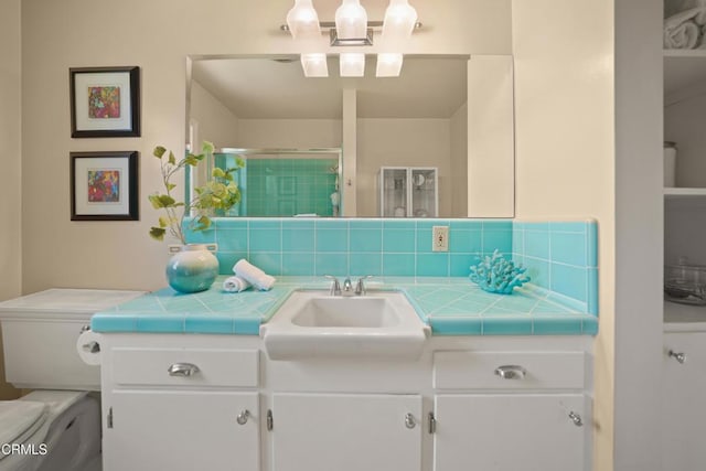 full bathroom featuring toilet, vanity, a stall shower, and backsplash