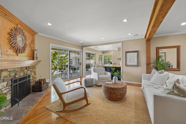 living area featuring light wood-type flooring, recessed lighting, ornamental molding, and a stone fireplace