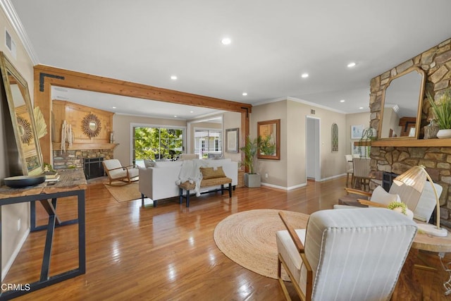 living area featuring crown molding, baseboards, recessed lighting, wood finished floors, and a stone fireplace