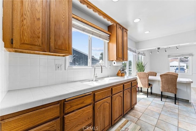 kitchen featuring backsplash, brown cabinetry, and a sink