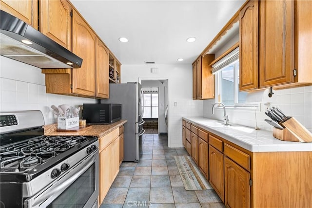 kitchen with a sink, stainless steel appliances, under cabinet range hood, recessed lighting, and backsplash