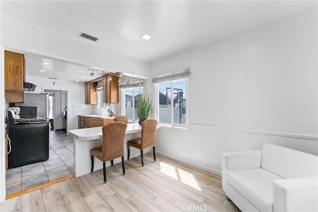 kitchen with range with gas stovetop, visible vents, light countertops, recessed lighting, and brown cabinetry