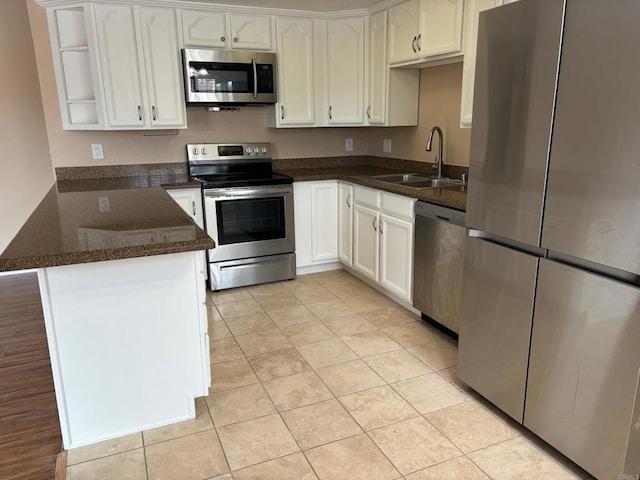 kitchen featuring stainless steel appliances, open shelves, white cabinets, a sink, and a peninsula