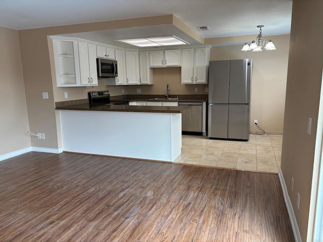 kitchen featuring open shelves, white cabinets, a sink, dark countertops, and stainless steel appliances