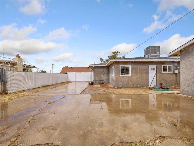rear view of house featuring fence, cooling unit, a patio area, and stucco siding