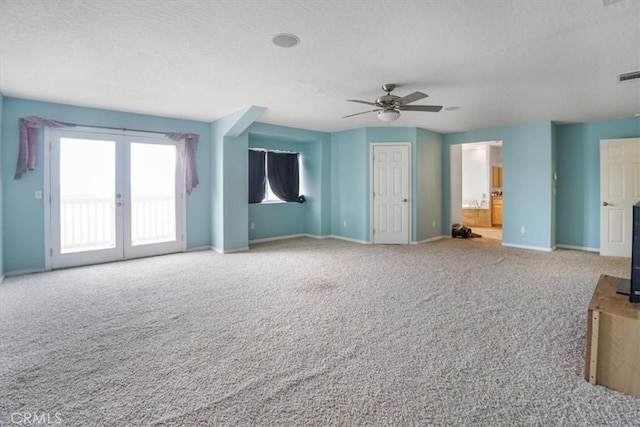 unfurnished living room with a ceiling fan, carpet flooring, a textured ceiling, and baseboards