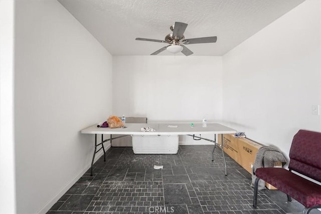 unfurnished office with baseboards, a ceiling fan, and a textured ceiling