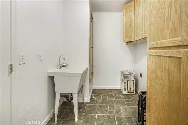 washroom with stone finish flooring and baseboards