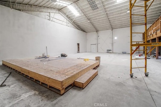 miscellaneous room featuring high vaulted ceiling and unfinished concrete floors