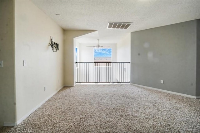 unfurnished room with a textured ceiling, visible vents, a ceiling fan, and carpet floors