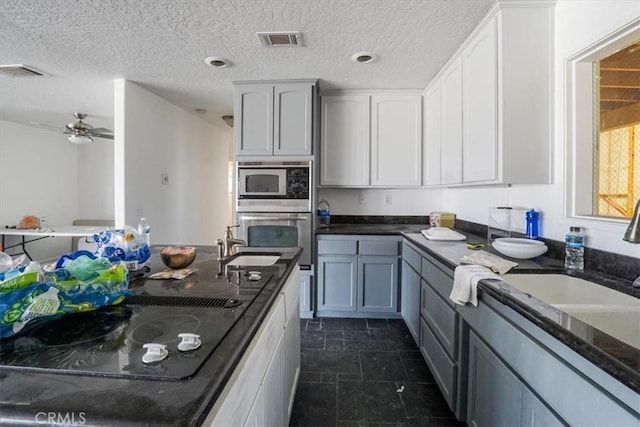 kitchen with dark stone countertops, visible vents, appliances with stainless steel finishes, and a sink