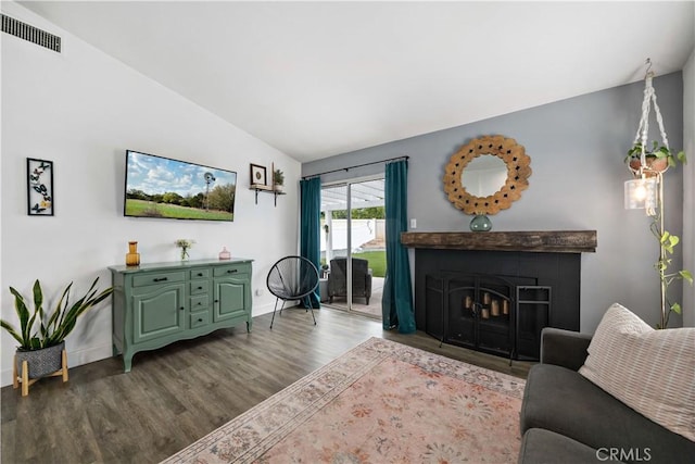 living room with wood finished floors, a fireplace, baseboards, visible vents, and lofted ceiling