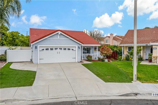 ranch-style house featuring driveway, a tiled roof, covered porch, a front yard, and fence