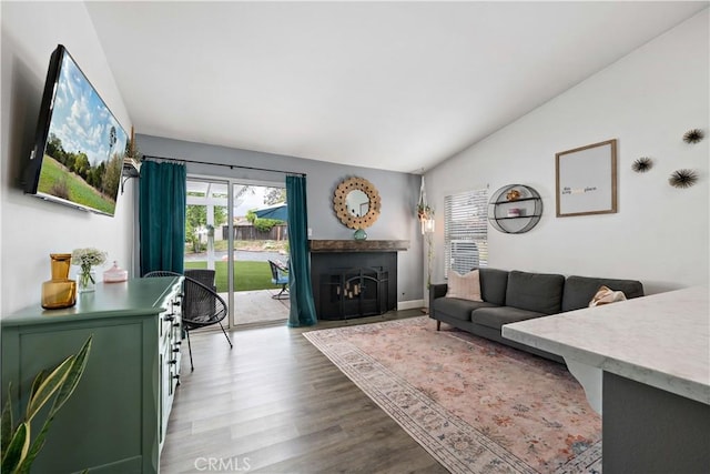 living area featuring lofted ceiling, wood finished floors, a fireplace, and baseboards