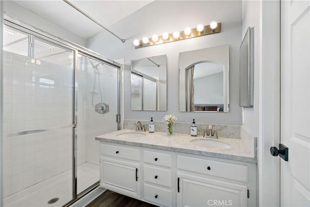 full bathroom featuring a stall shower, double vanity, and a sink